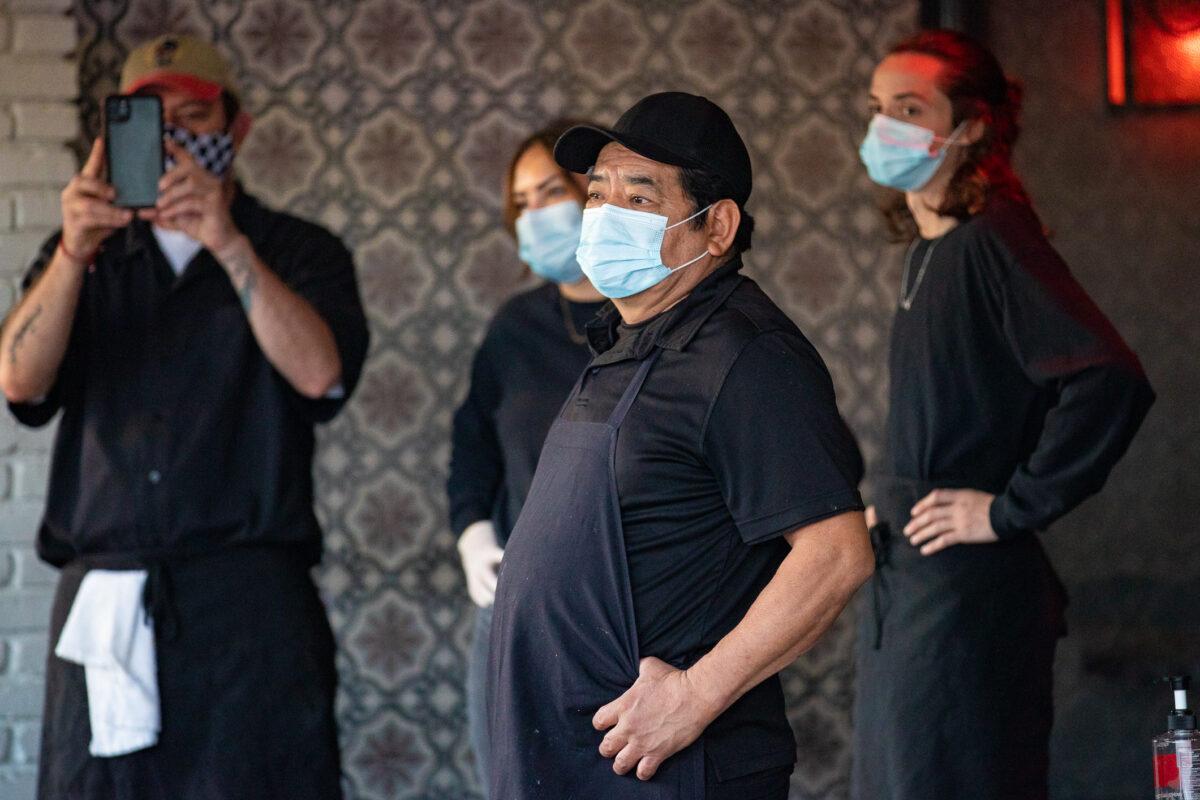 Restaurant workers watch demonstrators march peacefully down several blocks of Second St., in Long Beach, Calif., on Dec. 2, 2020. (John Fredricks/The Epoch Times)