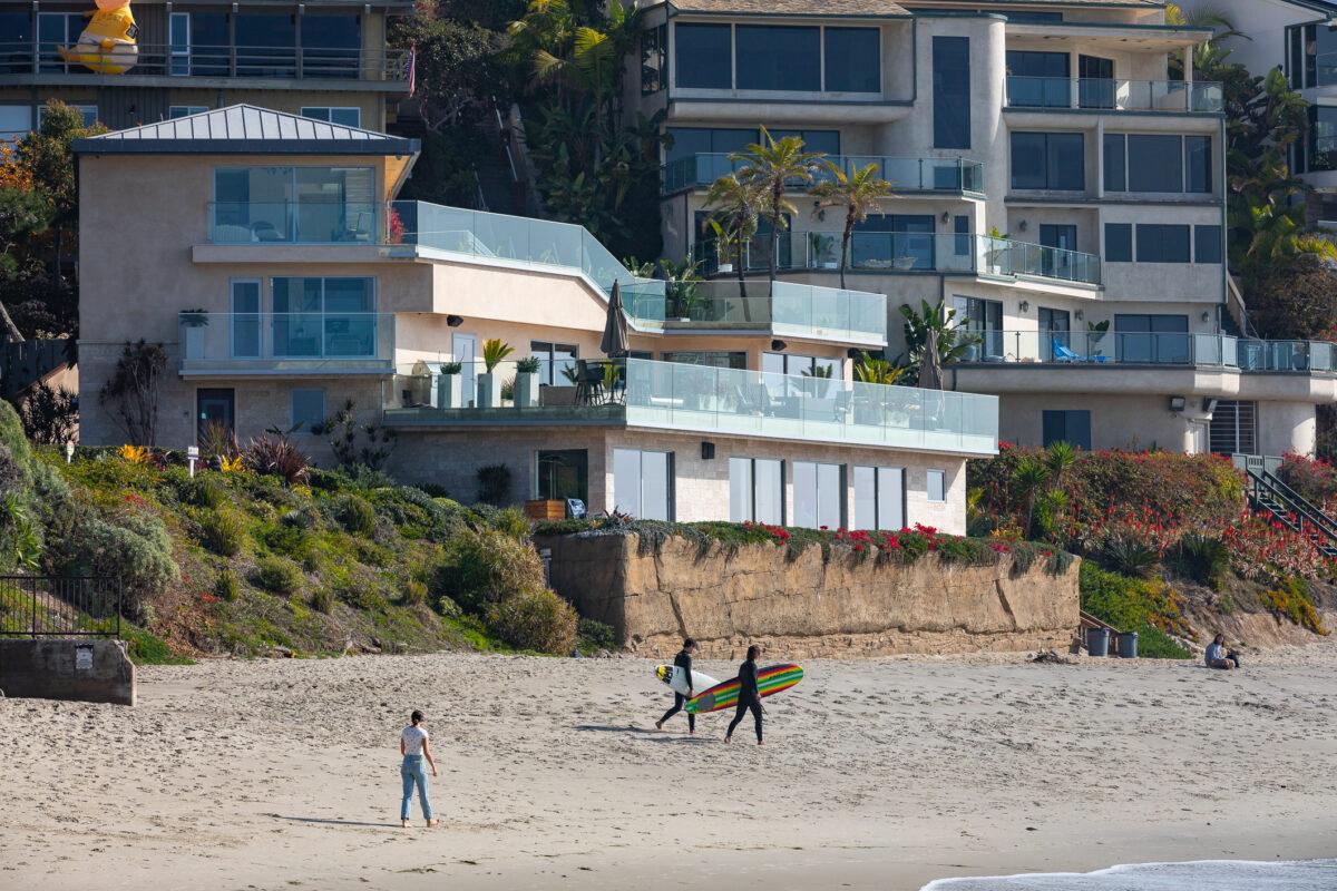 Surfers walk past a seawall built in front of a home at Victoria Beach, in the city of Laguna Beach, Calif., on Jan. 8, 2021. (John Fredricks/The Epoch Times)