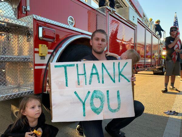 A father holding a sign expressing gratitude to the young Marines who had passed away, in La Verne, Calif., on Sept. 21, 2021. (Linda Jiang/The Epoch Times)