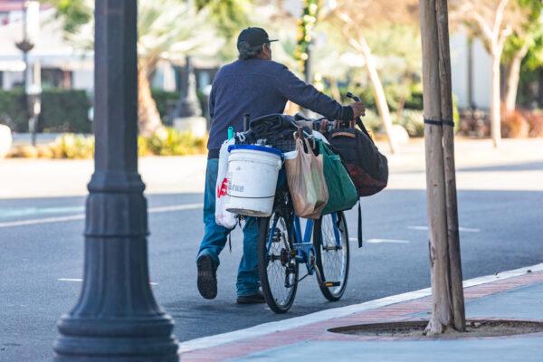 A homeless man walks with his bike and possessions in Santa Ana, Calif., on Dec. 17, 2020. (John Fredricks/The Epoch Times)