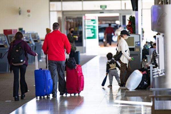 Travelers walk with thier baggage at John Wayne Airport, in Santa Ana, Calif., on Dec. 30, 2020. (John Fredricks/The Epoch Times)