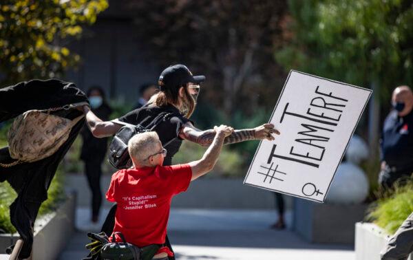 Counter protestor Joey Brite chases after an individual who stole one of her group's signs as protestors and counter-protestors voicing for or against a popular Dave Chapelle comedy special currently airing on Netflix gather in front of Netflix's Vine Street offices in Los Angeles on Oct. 20, 2021. (John Fredricks/The Epoch Times)