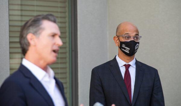 California Secretary of Health and Human Services Dr. Mark Ghaly listens to Governor Gavin Newsom speak in Los Angeles, Calif., on Nov. 10, 2021. (John Fredricks/The Epoch Times)
