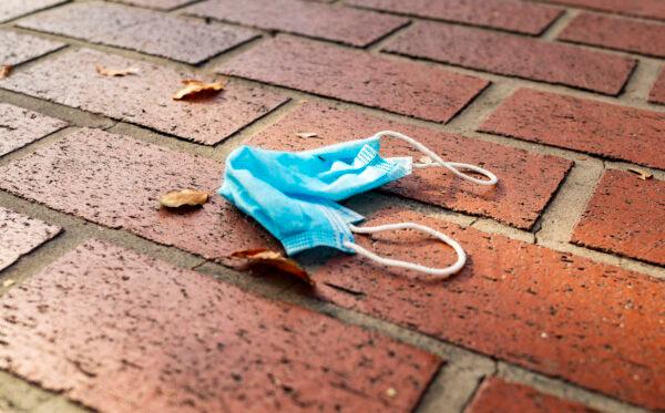 A mask lies discarded on a sidewalk in Orange, Calif., on June 19, 2020. (John Fredricks/The Epoch Times)