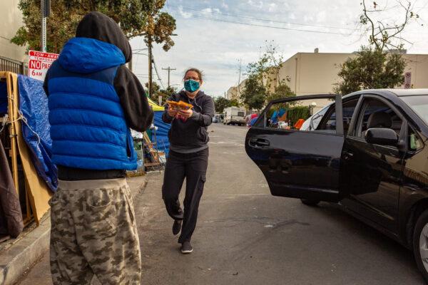 Venice Beach community members pass out items to the homeless community in Venice Beach, Calif., on Jan. 27, 2021. (John Fredricks/The Epoch Times)