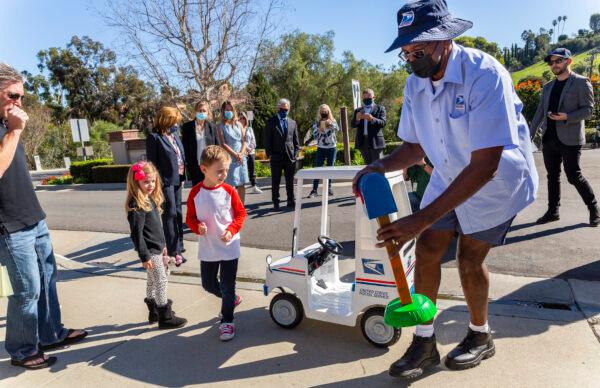 Seven-year-old Jacob Hayward receives gifts from his favorite mailman from the United States Postal Service, Van Singletary, at his home in Laguna Niguel, Calif., on Jan. 24, 2022. (John Fredricks/The Epoch Times)