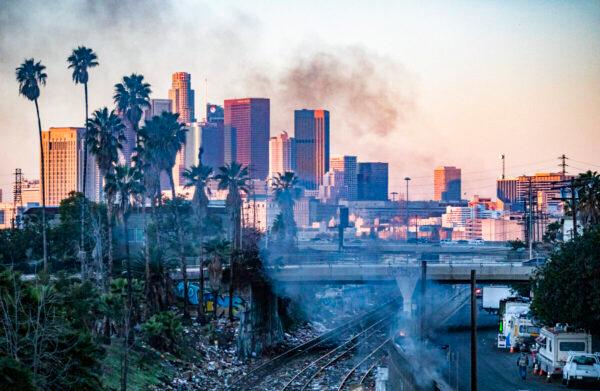 A fire burns in a homeless encampment while shredded boxes cover railroad tracks after ongoing theft in Los Angeles, Calif., on Jan. 20, 2022. (John Fredricks/The Epoch Times)