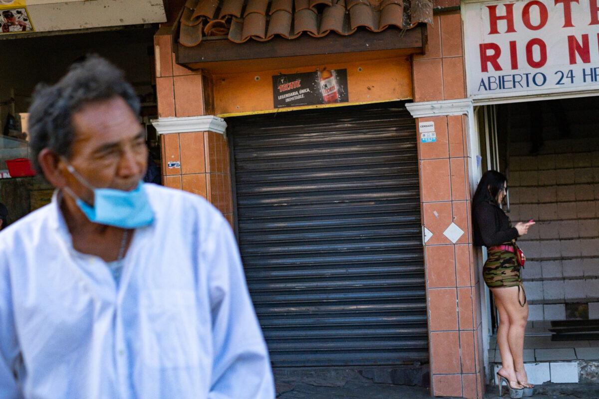 A woman stands with her phone near an entry to a hotel in Zona Norte, Tijuana, Mexico, on Jan 16, 2021. (John Fredricks/The Epoch Times)
