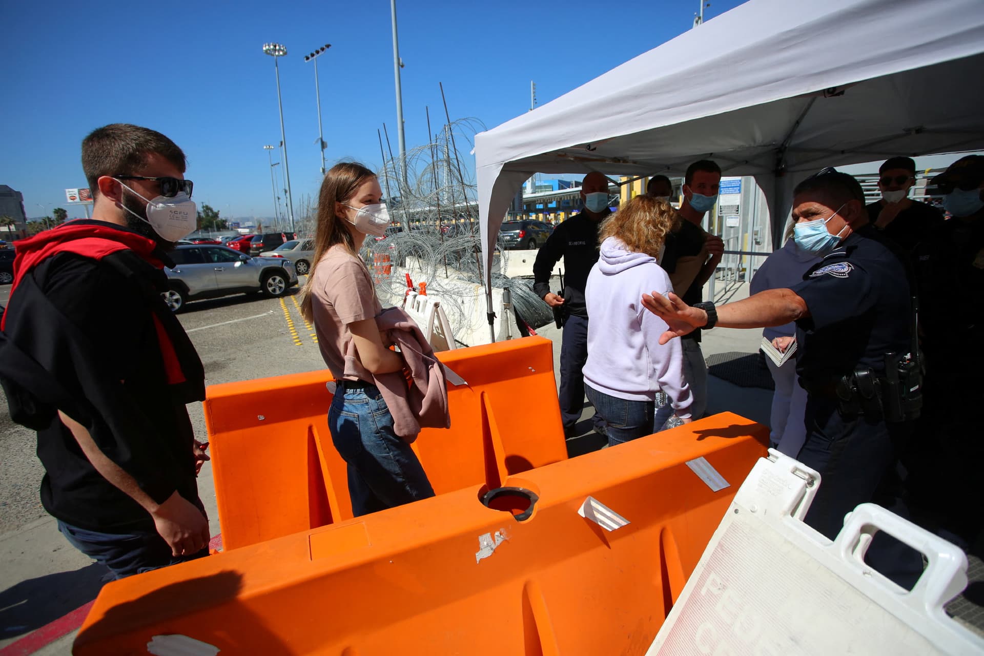 A U.S. Customs and Border Protection agent gestures toward a Ukrainian family at the San Ysidro Port of Entry at the U.S.–Mexico border in Tijuana, Mexico, on March 15, 2022. (Jorge Duenes/Reuters)