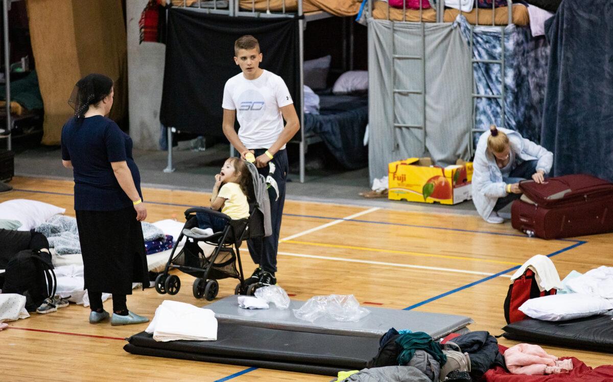 A family stands in the sleeping area in the Benito Juarez Sports Complex in Tijuana, Mexico, on April 27, 2022. (John Fredricks/The Epoch Times)