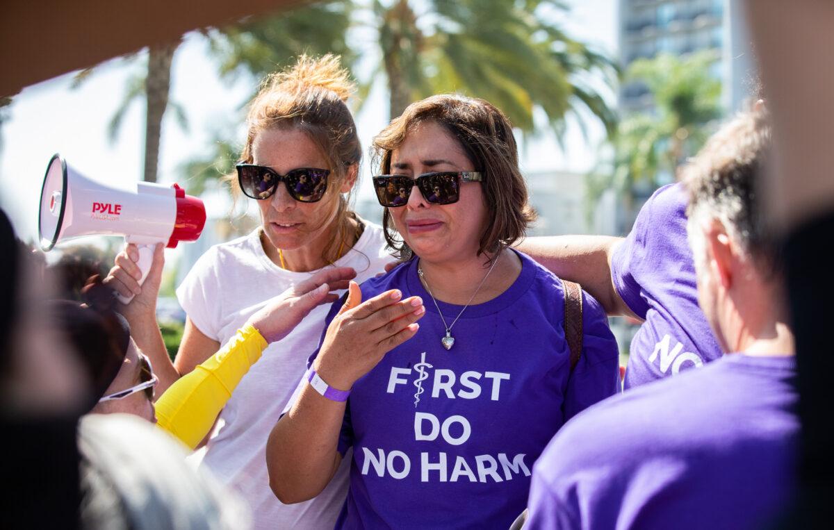 Abigail Martinez (R), the mother of a transgender teen who committed suicide, sheds tears as Erin Friday comforts her and transgender activists block TV cameras from capturing her story in Anaheim, Calif., on Oct. 8, 2022. (John Fredricks/The Epoch Times)