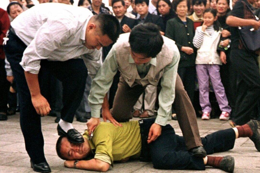 Police detain a Falun Gong practitioner on Tiananmen Square in Beijing on Oct. 1, 2000. (Chien-min Chung/AP Photo)