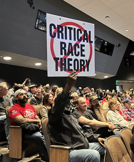 A man holds up a sign against critical race theory at a school board meeting in Temecula, Calif., on Dec. 13, 2022. (The Epoch Times)