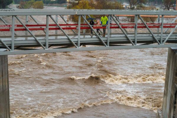 People cross a bridge over a swollen Los Angeles River in Los Angeles on Jan. 14, 2023. (Damian Dovarganes/AP Photo)