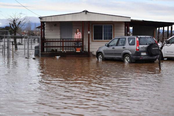 A woman waits for her husband at their front porch to be rescued from their flooded home in Brentwood, Calif., on Monday, Jan. 16, 2023. (Jose Carlos Fajardo/Bay Area News Group via AP)