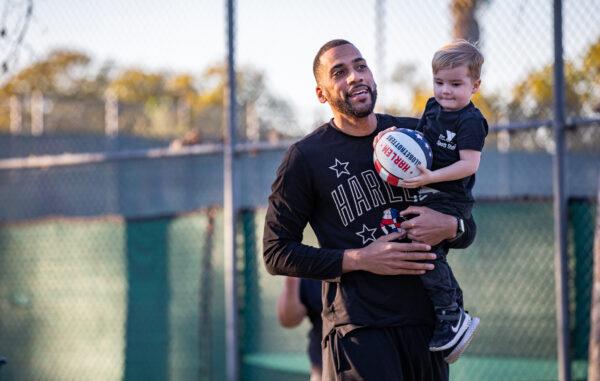 Harlem Globetrotter "Zeus" McClurkin helps a child slam dunk on a basketball hoop in Fullerton, Calif., on Feb. 1, 2023. (John Fredricks/The Epoch Times)