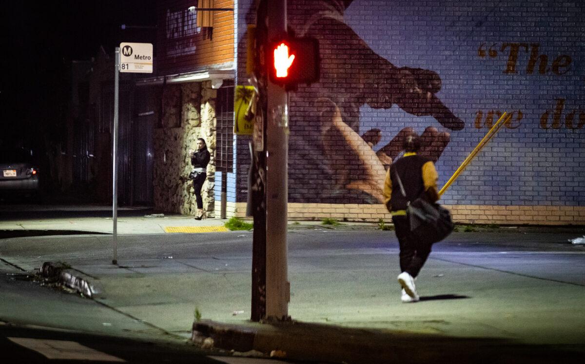 A woman waits in an area known for prostitution near Figueroa and 69th streets in Los Angeles on Feb. 8, 2023. (John Fredricks/The Epoch Times)