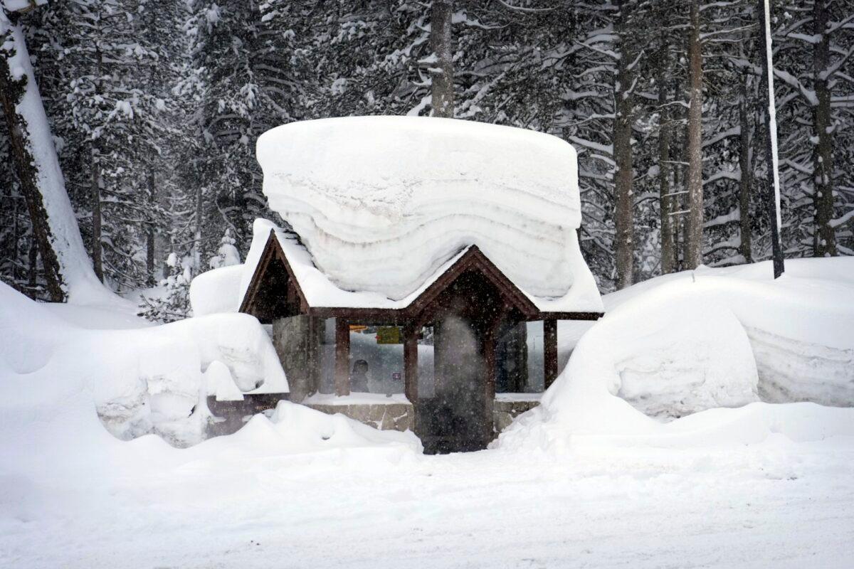 A person sits in a snow-covered bus stop in Olympic Valley, Calif., on Feb. 24, 2023. (John Locher/AP Photo)