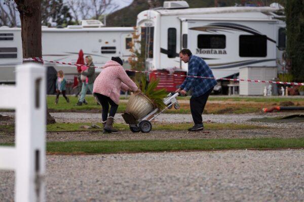 Residents move belongings away from the Santa Clara River as it floods due to heavy rain, washing away over 150 feet of land and multiple RV homes in Castaic, Calif., on Feb. 25, 2023. (Allison Dinner/AFP via Getty Images)