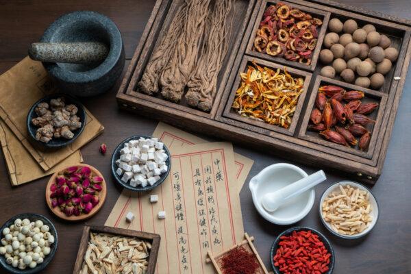 Ancient Chinese medicine books and herbs are on the table. (Shutterstock)