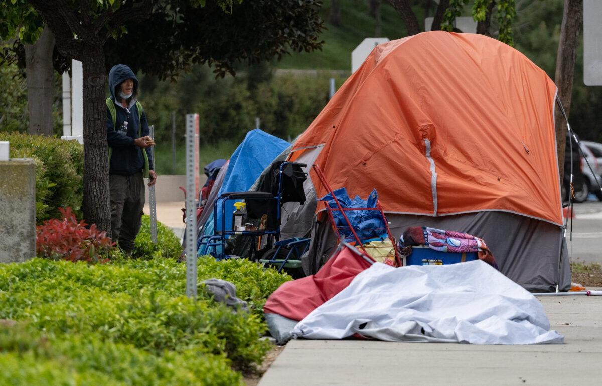 A homeless woman stands next to her sidewalk encampment in Newport Beach, Calif., on May 1, 2023. (John Fredricks/The Epoch Times)
