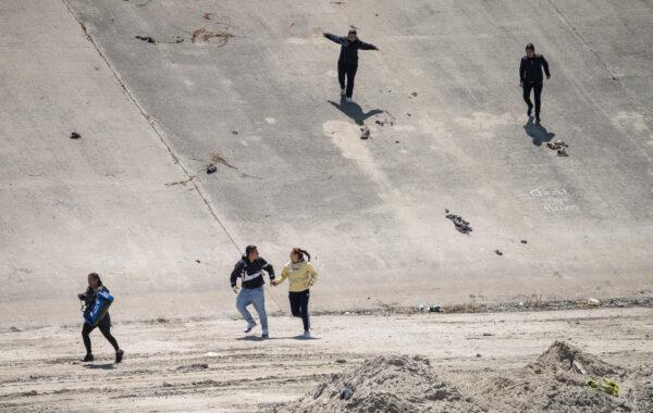 Migrants cross the Tijuana River toward the U.S. border in Tijuana, Mexico, on May 11, 2023. (John Fredricks/The Epoch Times)