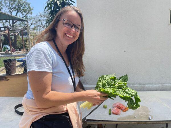 Homeless program volunteer Staci Loveridge hands out Swiss chard grown from St. Luke's Episcopal Church’s community garden in Long Beach, Calif., on May 13, 2023. (Carol Cassis/The Epoch Times)
