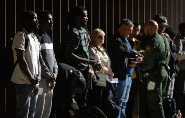 Illegal immigrants wait to be transported by bus to Border Patrol processing facilities in Yuma, Ariz., on May 18, 2023. (John Fredricks/The Epoch Times)