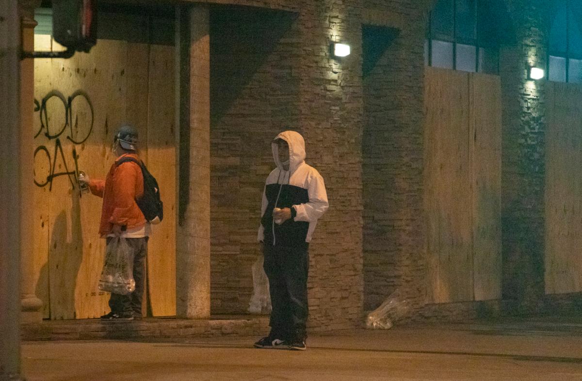 Men write graffiti on boarded up businesses in Los Angeles on Nov. 5, 2020. (John Fredricks/The Epoch Times)