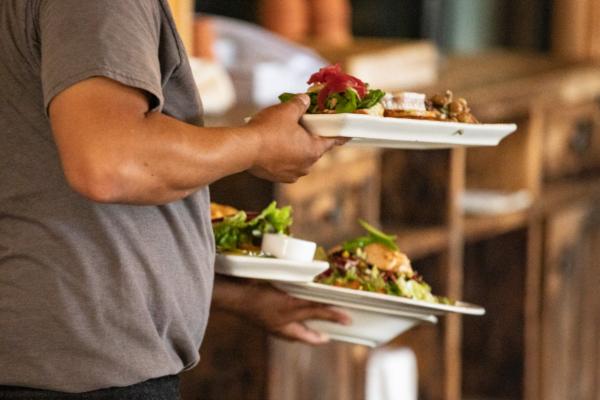 A waiter carries food at The Farmhouse restaurant in Newport Beach, Calif., on Sept. 9, 2020. (John Fredricks/The Epoch Times)