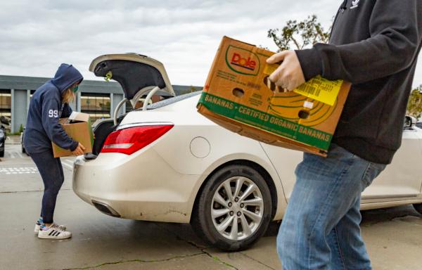 Volunteers at Laguna Niguel Presbyterian work with San Clemente-based Family Assistance Ministries in handing out food donations to a line of cars in Laguna Niguel, Calif., on Dec. 23, 2021. (John Fredricks/The Epoch Times)