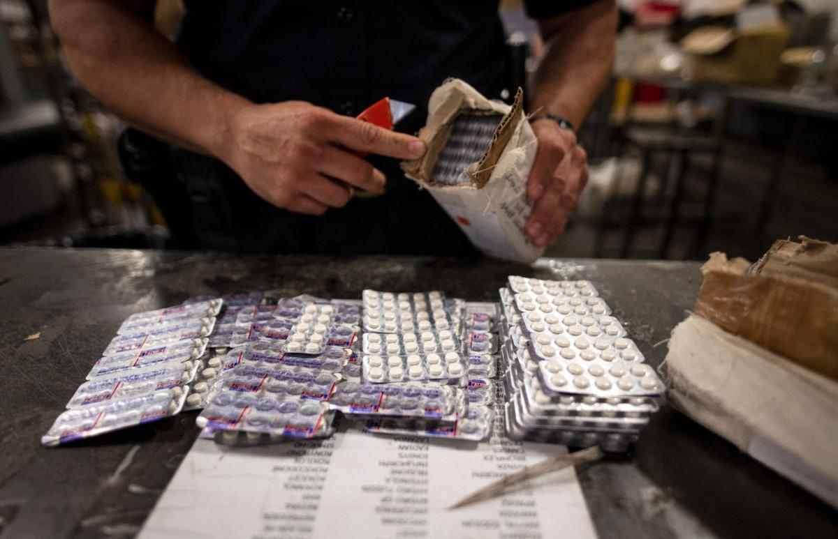 An officer from the U.S. Customs and Border Protection, Trade and Cargo Division finds Oxycodone pills in a parcel at John F. Kennedy Airport's US Postal Service facility in New York on June 24, 2019. (Johannes Eisele/AFP via Getty Images)