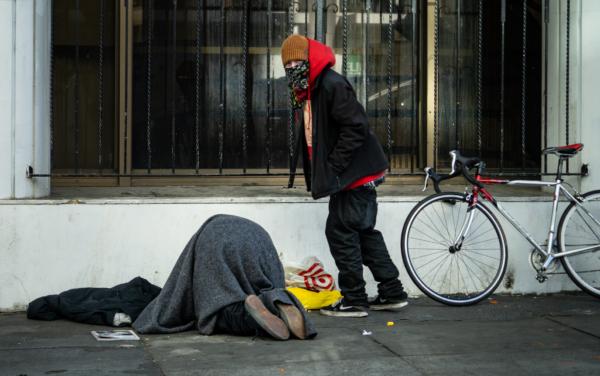 A man watches a person use drugs in San Francisco, Calif., on Feb, 22, 2023. (John Fredricks/The Epoch Times)