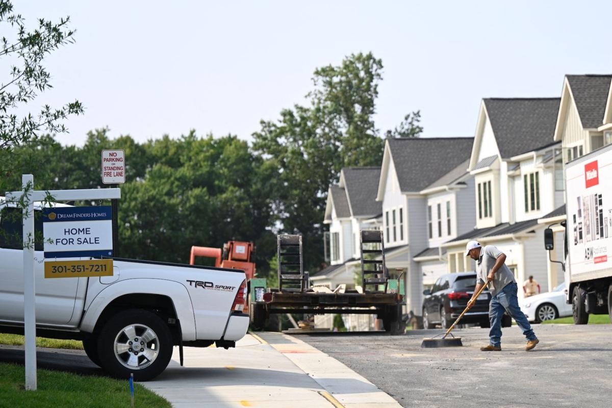 A "For Sale" sign is displayed in front of a new home in a housing development as a maintenance worker sweeps the street in Fairfax, Va., on Aug. 22, 2023. (Andrew Caballero-Reynolds/AFP via Getty Images)
