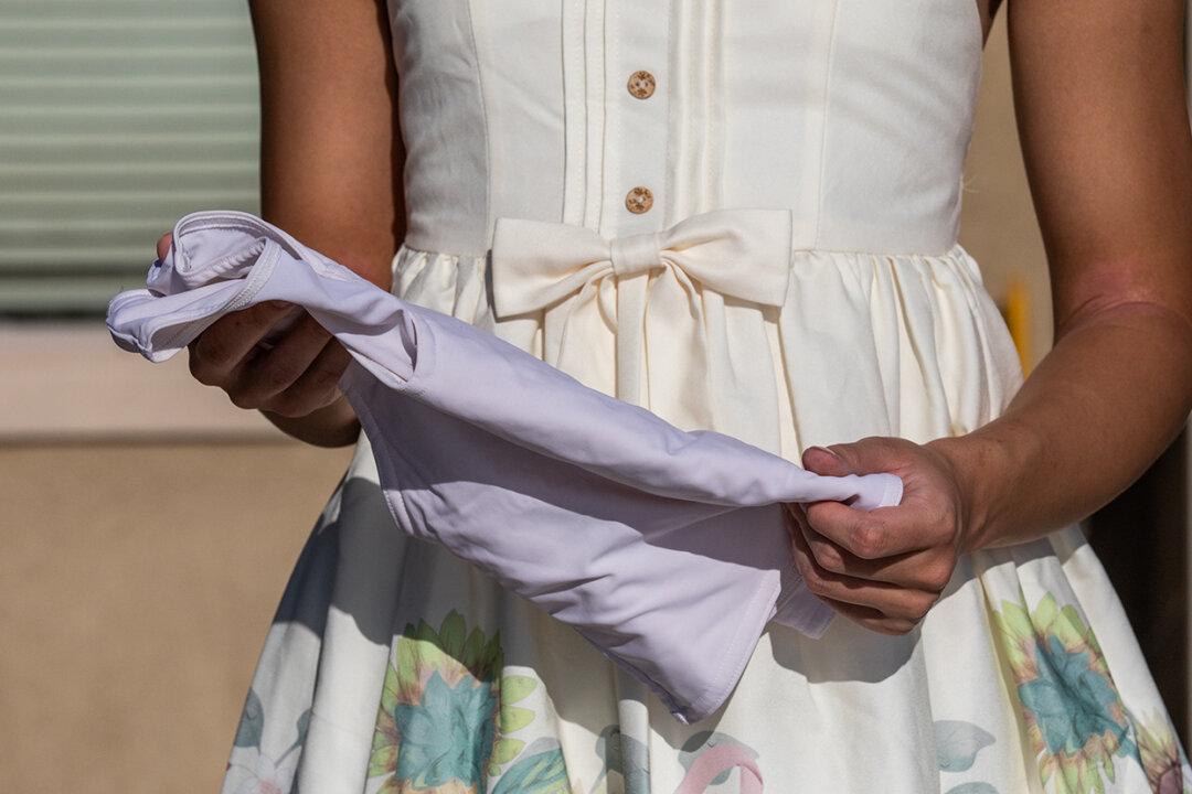 A girl holds a body brace that she used while taking hormonal treatments for transitioning into a male, in Northern California on Aug. 26, 2022. (John Fredricks/The Epoch Times)