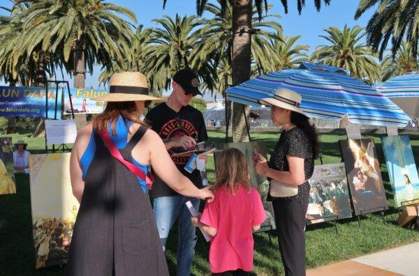 People checking out the Falun Dafa art exhibit at the 22nd annual Irvine Global Village Festival in Irvine, Calif., on Oct. 14, 2023. (Sophie Li/The Epoch Times)