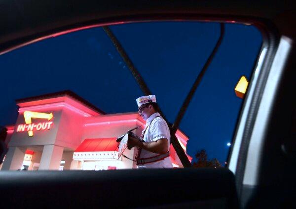 An employee takes orders from drivers waiting in the drive-thru lane at an In-N-Out Burger restaurant in Alhambra, Calif., on Aug. 30, 2018. (Frederic J. Brown/AFP via Getty Images)
