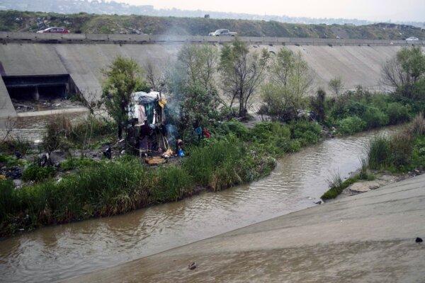 A homeless woman stands outside her shaft on the Alamar stream, part of the Tijuana River watershed, in Tijuana, Baja California state, Mexico, on March 14, 2020. (Guillermo Arias/AFP via Getty Images)
