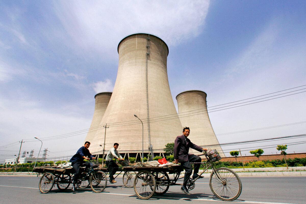 Migrant workers ride their tricycles past water-cooling towers at a coal-fired power plant on the outskirts of Beijing on May 4, 2007. (Frederic J. Brown/AFP via Getty Images)