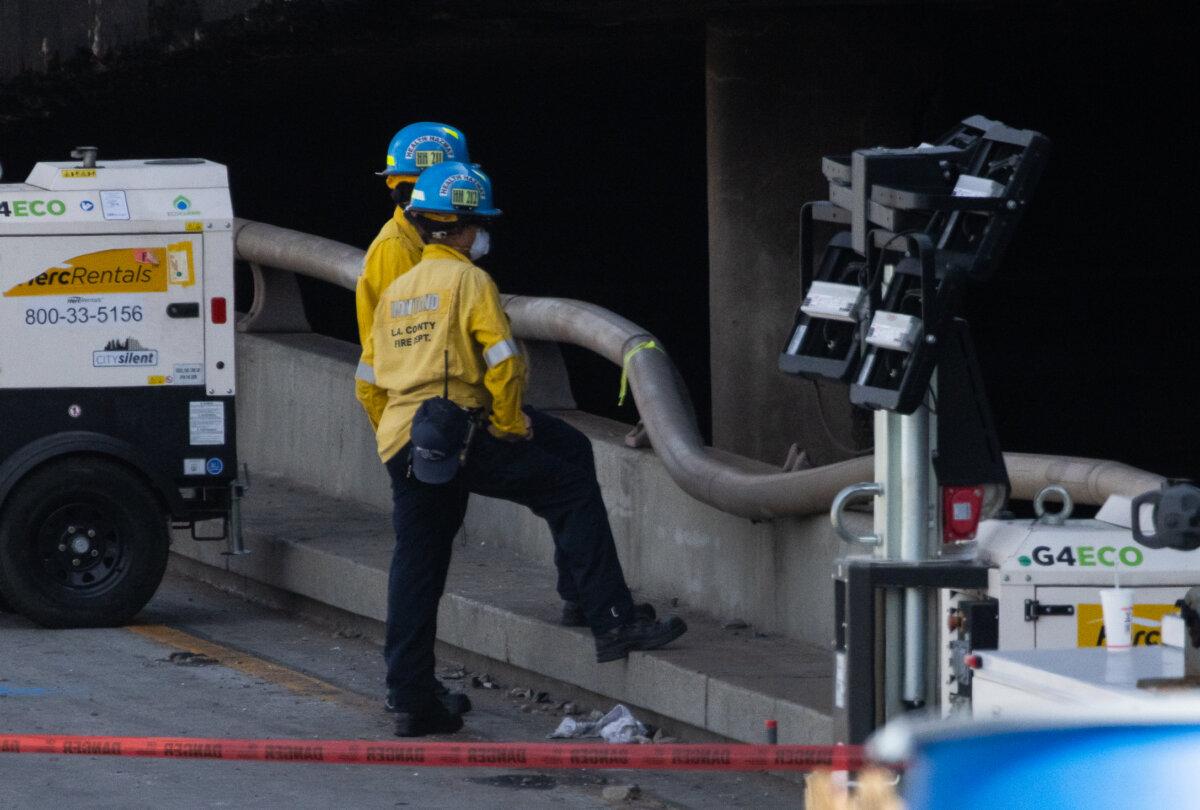 Firefighters look at damage caused by a powerful fire that resulted in a temporary closure of the 10 Freeway in Los Angeles on Nov. 13, 2023. (John Fredricks/The Epoch Times)