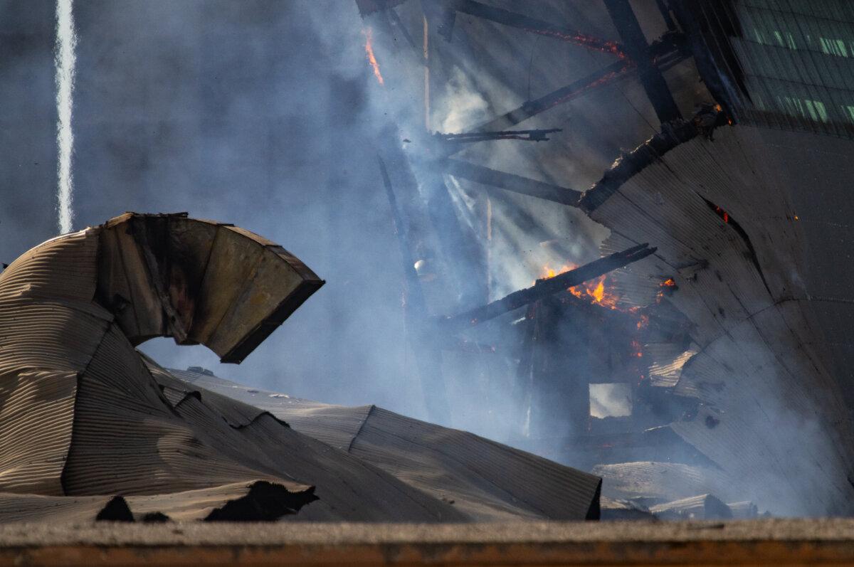A fire continues to burn a historic blimp hangar in Tustin, Calif., on Nov. 14, 2023. (John Fredricks/The Epoch Times)