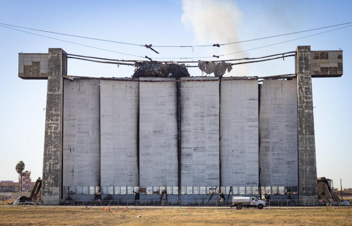 A water truck drives toward a clean up crew as a fire continues to burn a historic blimp hangar in Tustin, Calif., on Nov. 14, 2023. (John Fredricks/The Epoch Times)