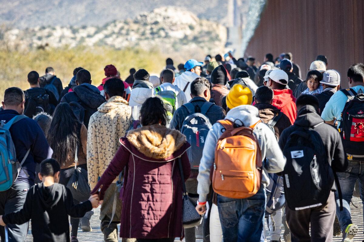 Illegal immigrants who passed through a gap in the U.S. border wall await processing by Border Patrol agents in Jacumba, Calif., on Dec. 7, 2023. (John Fredricks/The Epoch Times)