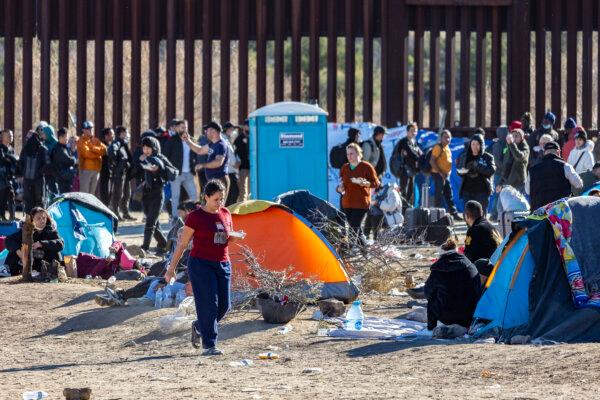 Illegal immigrants who passed through a gap in the U.S. border wall await processing by Border Patrol agents in Jacumba, Calif., on Dec. 7, 2023. (John Fredricks/The Epoch Times)