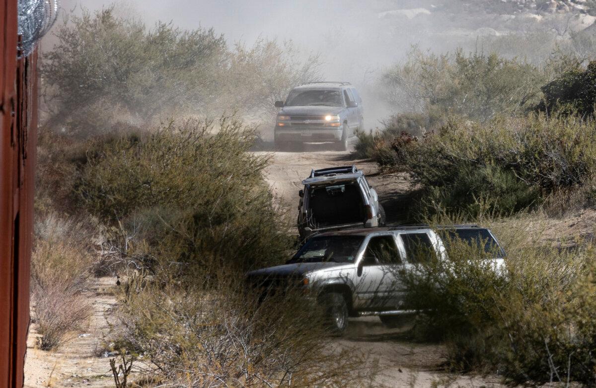 Suspected Mexican cartel members drive SUVs containing dozens of illegal immigrants to a gap in the U.S. border wall near Jacumba, Calif., on Dec. 6, 2023. (John Fredricks/The Epoch Times)