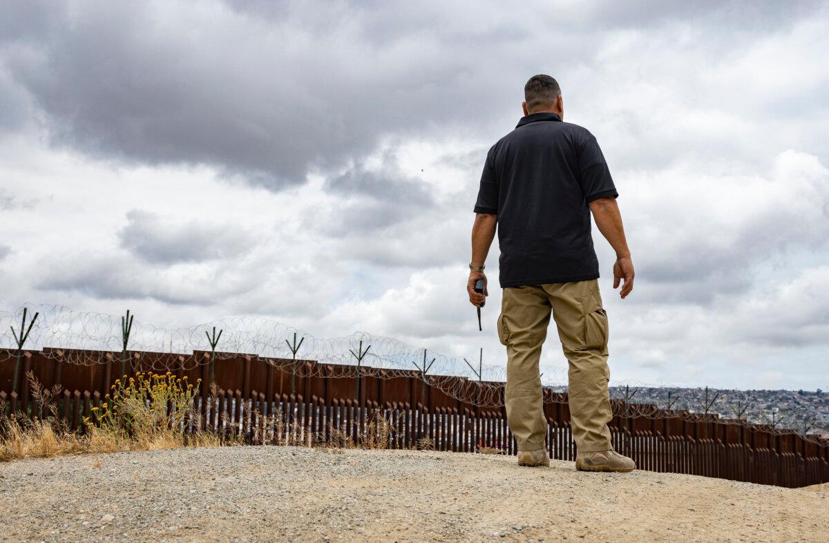 Manny Bayon, a Border Patrol agent, listens to radio chatter near the border wall in San Diego on May 31, 2023. (John Fredricks/The Epoch Times)