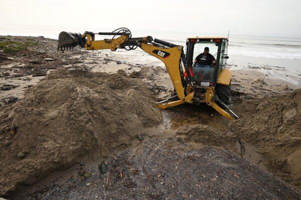 A heavy equipment operator removes sand and debris after huge waves caused damage and injuries, in Ventura, Calif., on Dec. 29, 2023. (Robyn Beck/AFP via Getty Images)