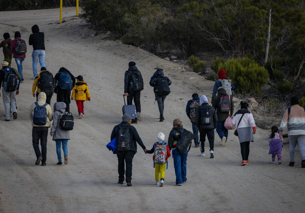 Illegal immigrants gather after crossing the United States border wall in Jacumba, Calif., on Jan. 10, 2024. (John Fredricks/The Epoch Times)