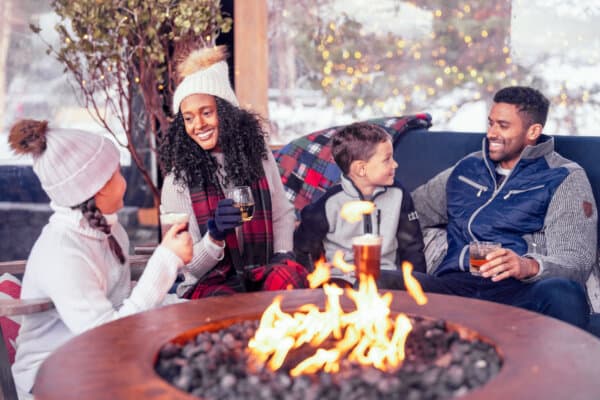 A family enjoys an outdoor fire pit at Spruce Peak Village. (Courtesy of The Lodge at Spruce Peak)