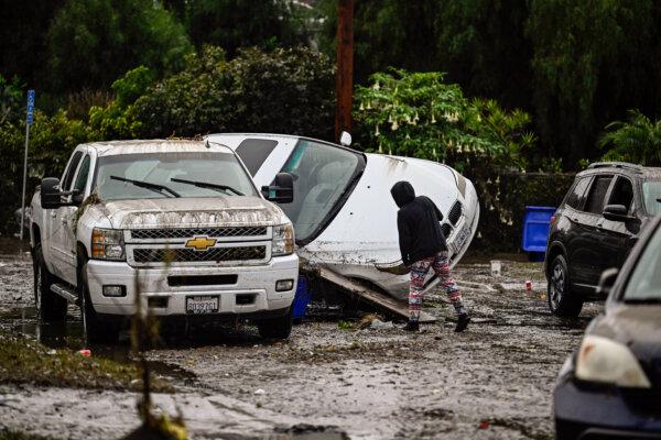 A woman examines cars damaged from floods during a rain storm, in San Diego on Jan. 22, 2024. (Denis Poroy/AP Photo)